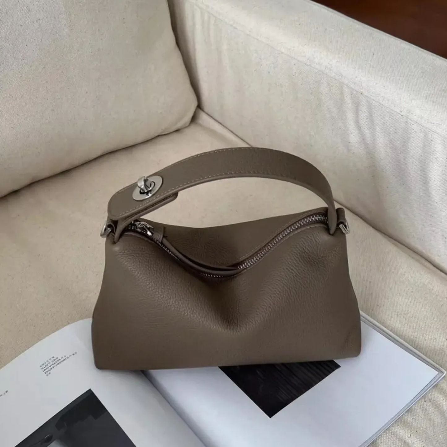 Grey Slouchy Rectangular Handbag With Curved Top Grip, Silver Turnlock Fastener, Curved Zipper Closure And Side Metal Ring Fittings