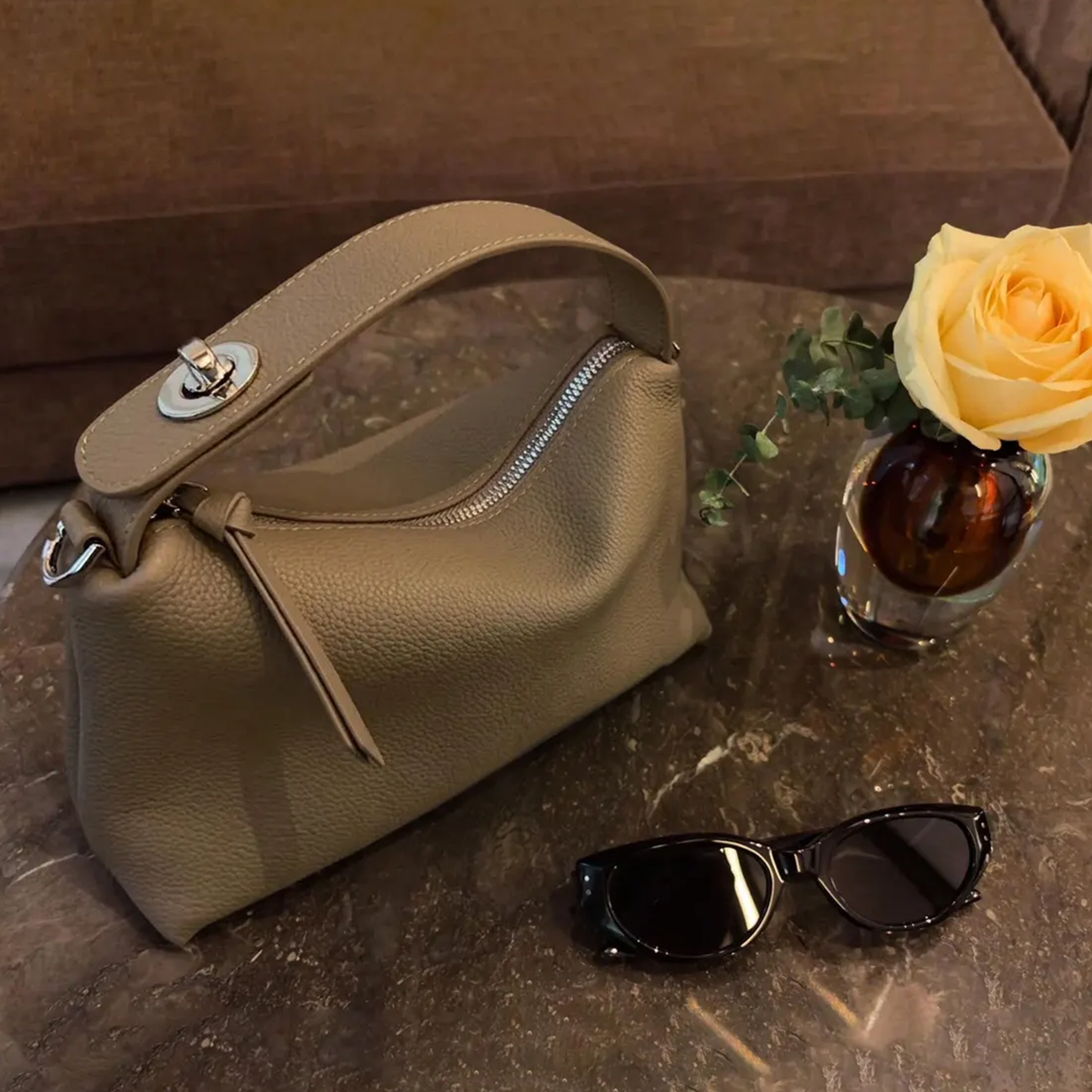Grey Slouchy Rectangular Handbag With Curved Top Grip, Silver Turnlock Fastener, Curved Zipper Closure And Side Metal Ring Fittings