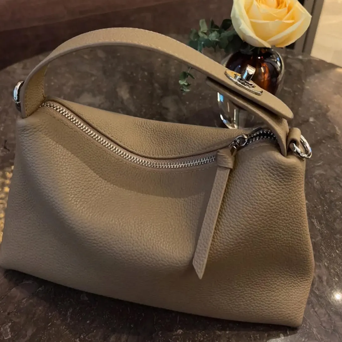 Grey Slouchy Rectangular Handbag With Curved Top Grip, Silver Turnlock Fastener, Curved Zipper Closure And Side Metal Ring Fittings