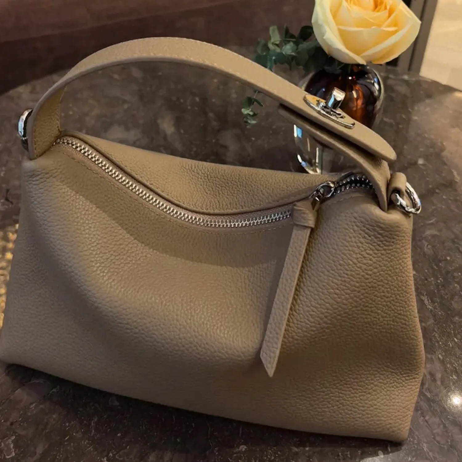 Grey Slouchy Rectangular Handbag With Curved Top Grip, Silver Turnlock Fastener, Curved Zipper Closure And Side Metal Ring Fittings