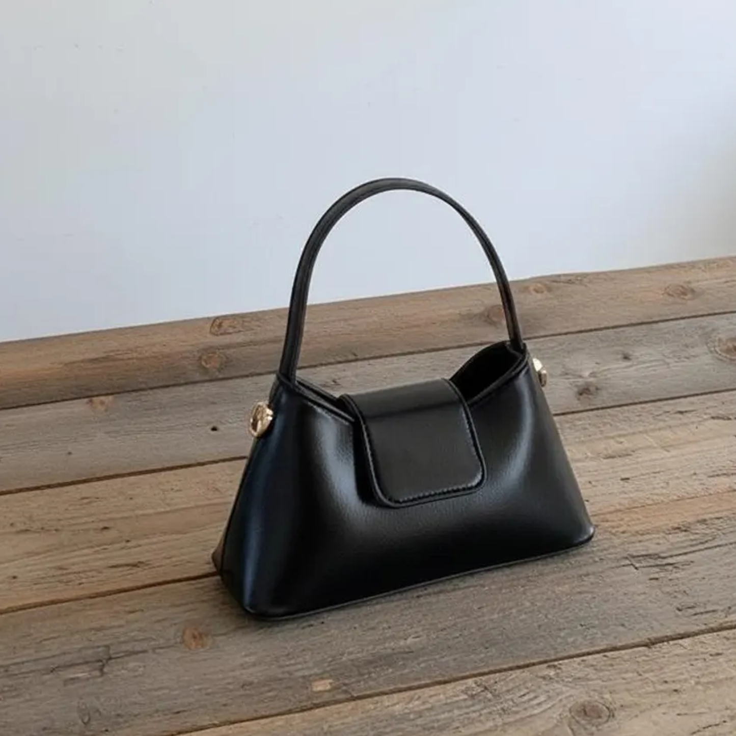 Solid Black Tapered Trapezoid Mini Satchel With Curved Slim Top Handle, Metallic Side Stud Accents And Rectangular Magnetic Front Flap Panel