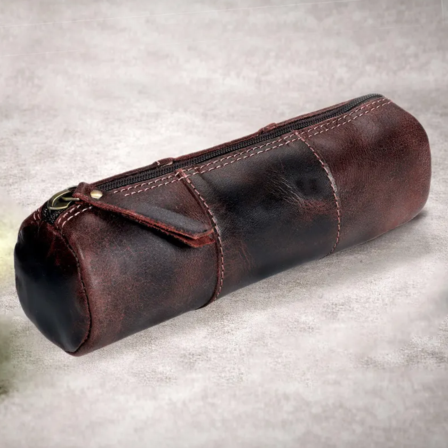 Weathered Dark Brown Cylindrical Stationery Pouch With Segmented Stitched Panels, Full Length Top Zipper And Metal Stud Reinforced Fabric Pull Tab